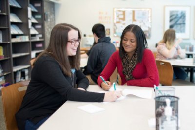 A writing consultant sits next to a student and reviews a piece of writing